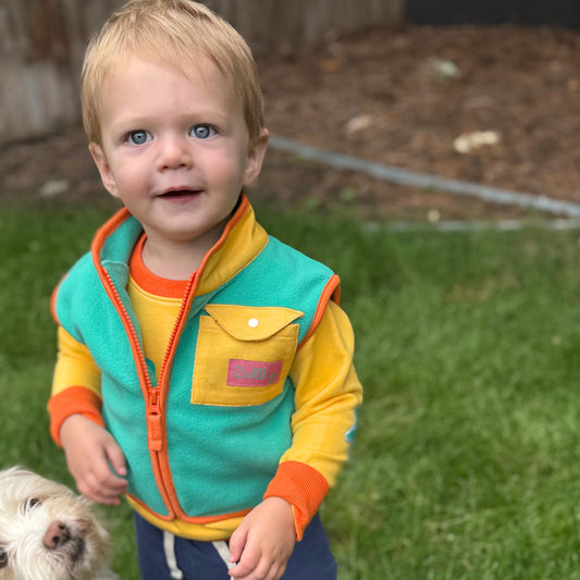 Colorful toddler vest in teal and yellow with front pocket, perfect for outdoor play.