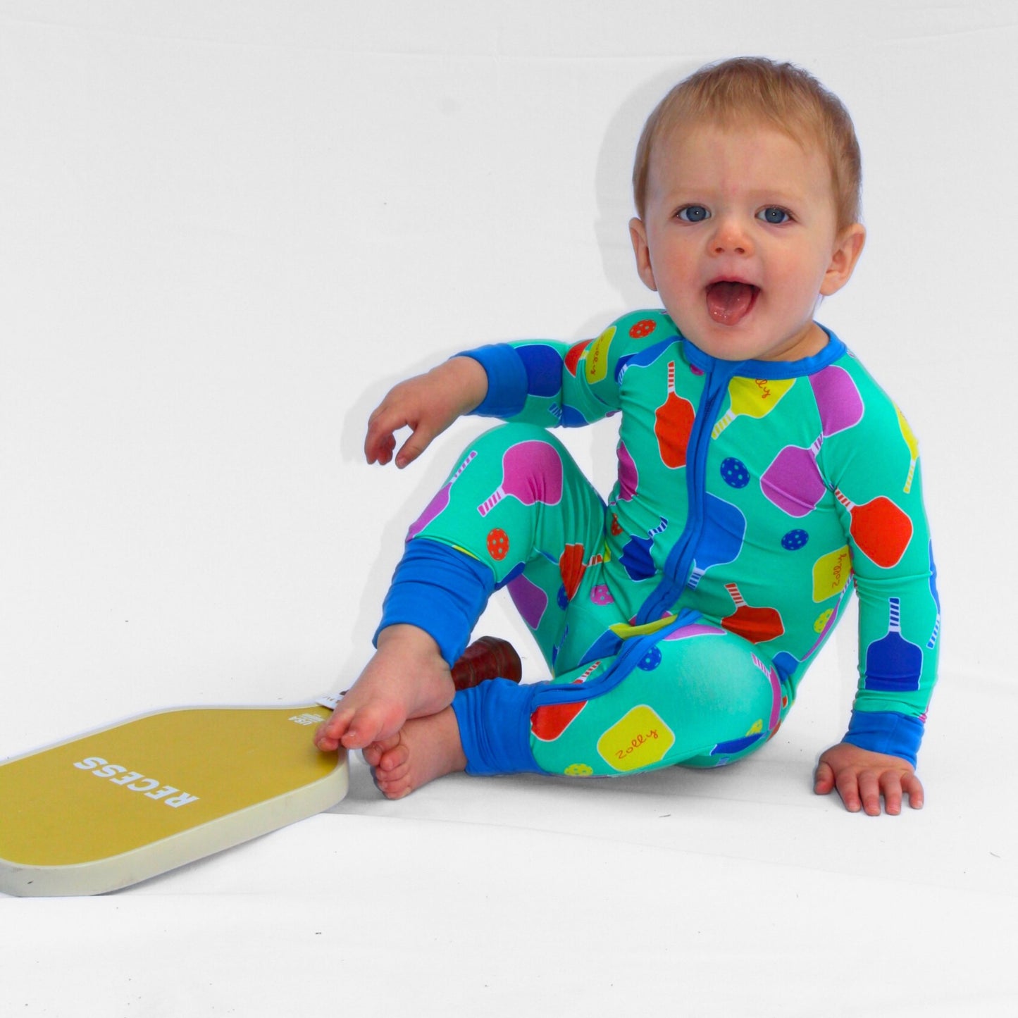 Colorful baby onesie in green, featuring playful food patterns, made from soft, stretchy material.