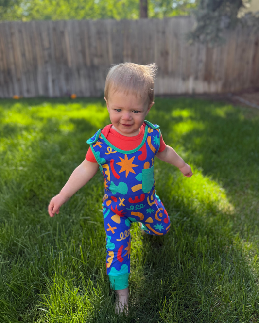 Colorful toddler jumpsuit, blue with playful patterns, perfect for outdoor play and made from soft fabric.