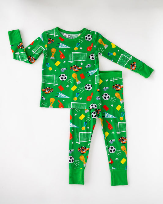 Kids' long-sleeve soccer-themed pajamas in vibrant green, featuring playful graphics on soft fabric.