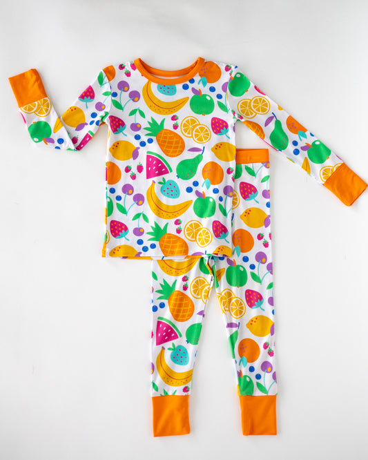 Colorful kids' pajamas set featuring fruit patterns, long sleeves, and orange trim, made from soft cotton material.