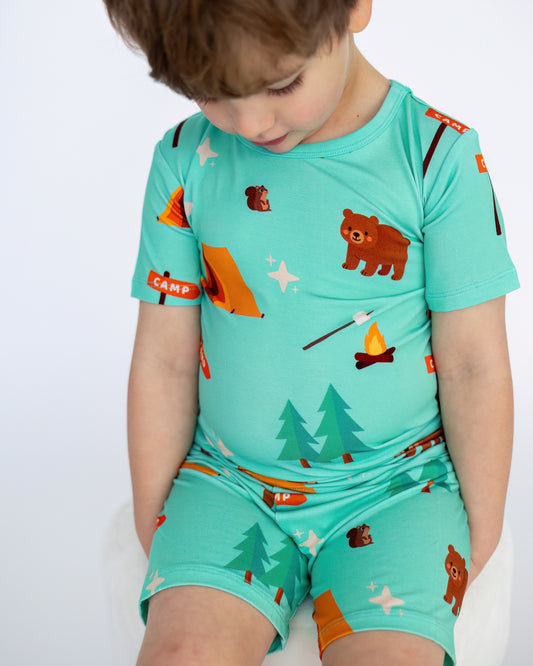 Boys' camp-themed pajamas in turquoise, featuring bears, tents, and trees, made from soft cotton.