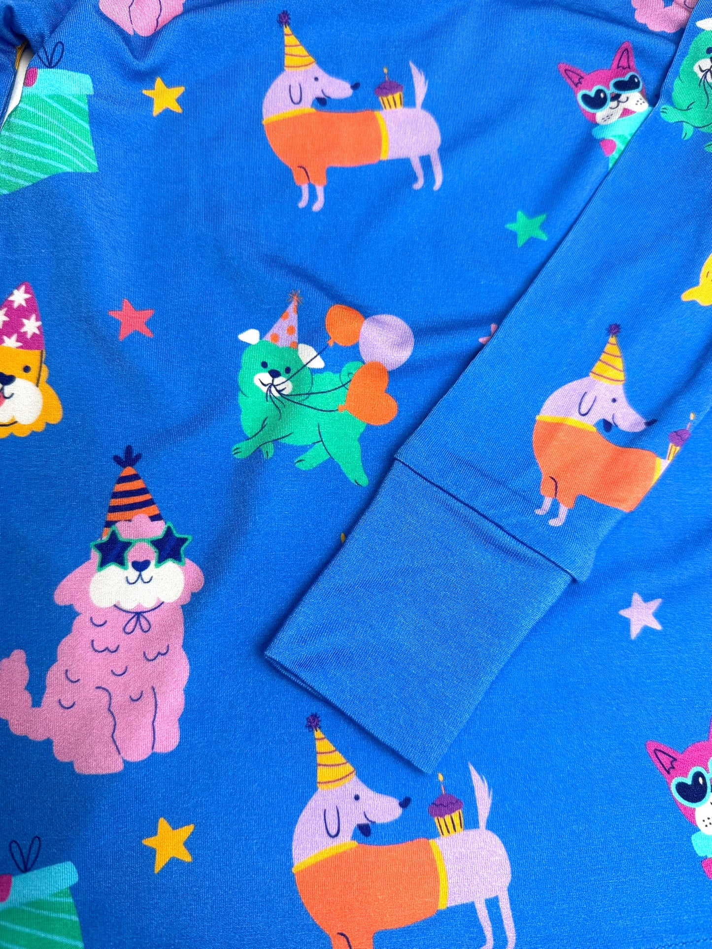 Colorful blue fabric featuring playful cartoon dogs in party hats, perfect for fun children's clothing.