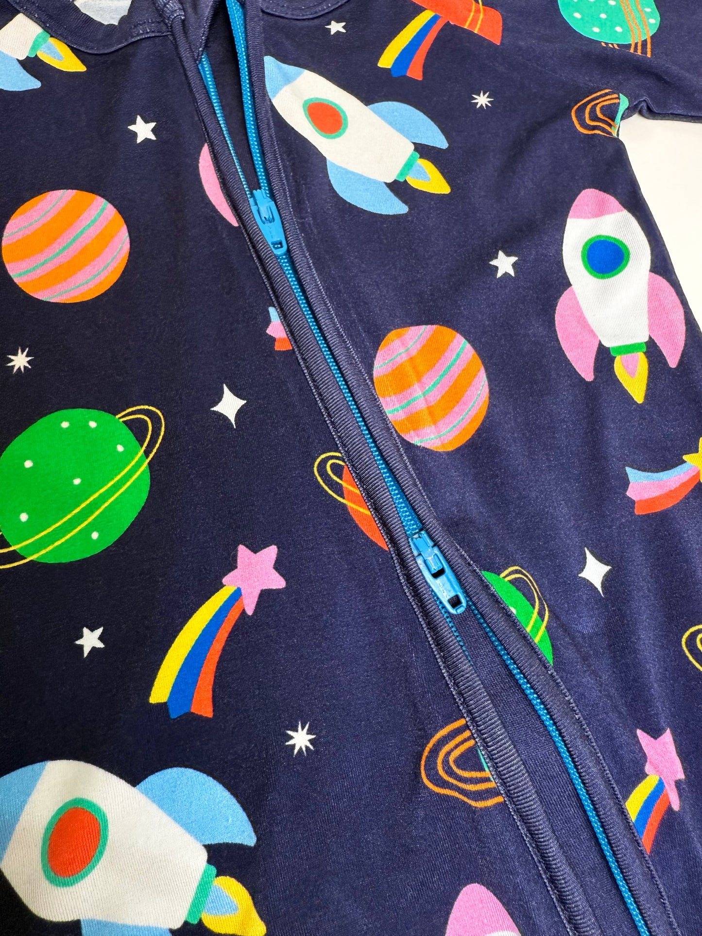 Navy blue kids' jumpsuit featuring colorful rocket, planet, and star print, crafted from soft, comfortable fabric.
