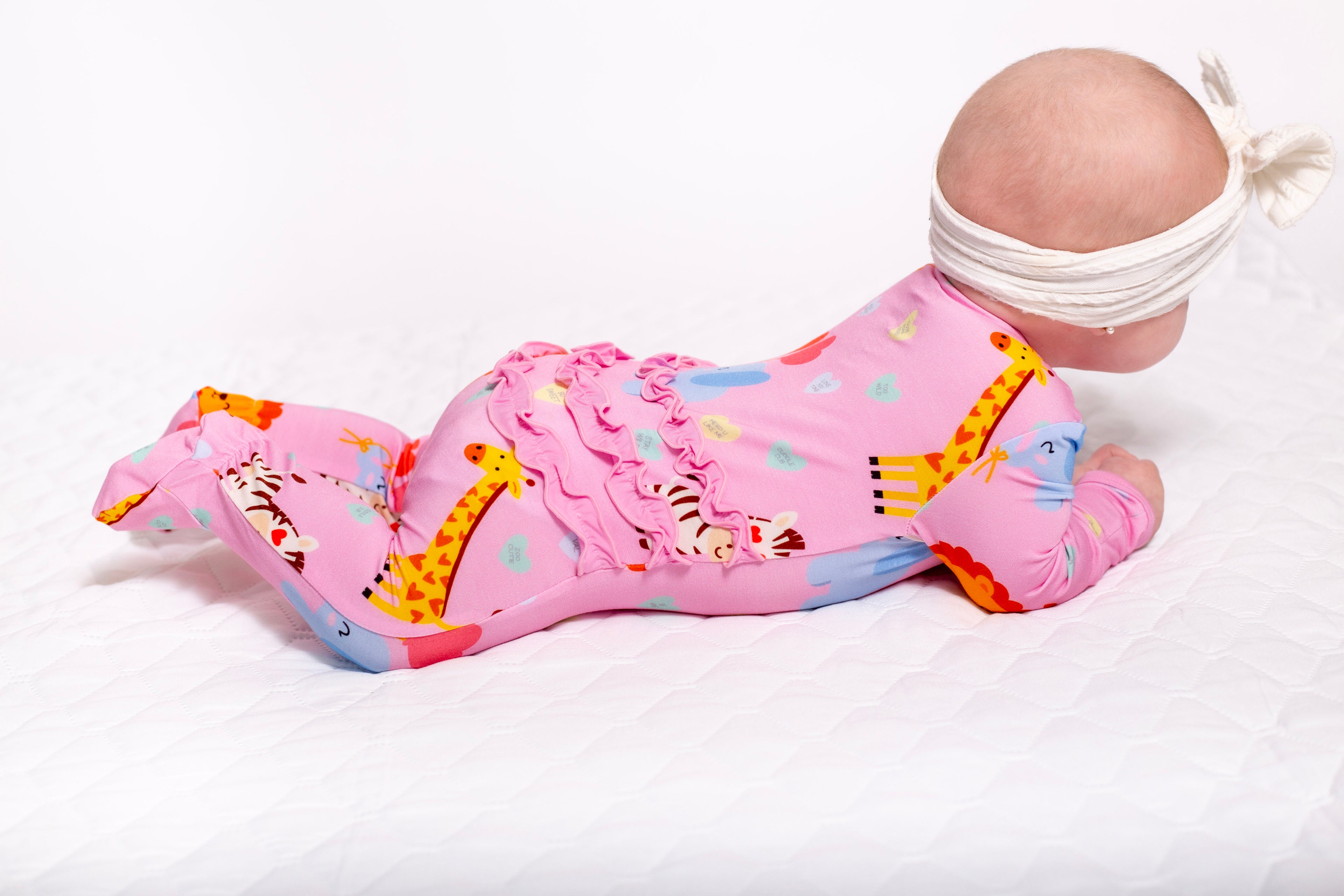 Pink baby bouncer with cartoon designs on a white background