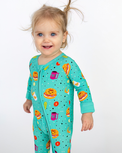 Cute turquoise toddler onesie featuring fun food patterns, made from soft cotton fabric, perfect for playtime.