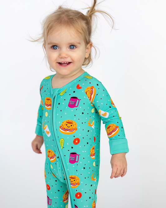 Cute turquoise toddler onesie featuring fun food patterns, made from soft cotton fabric, perfect for playtime.