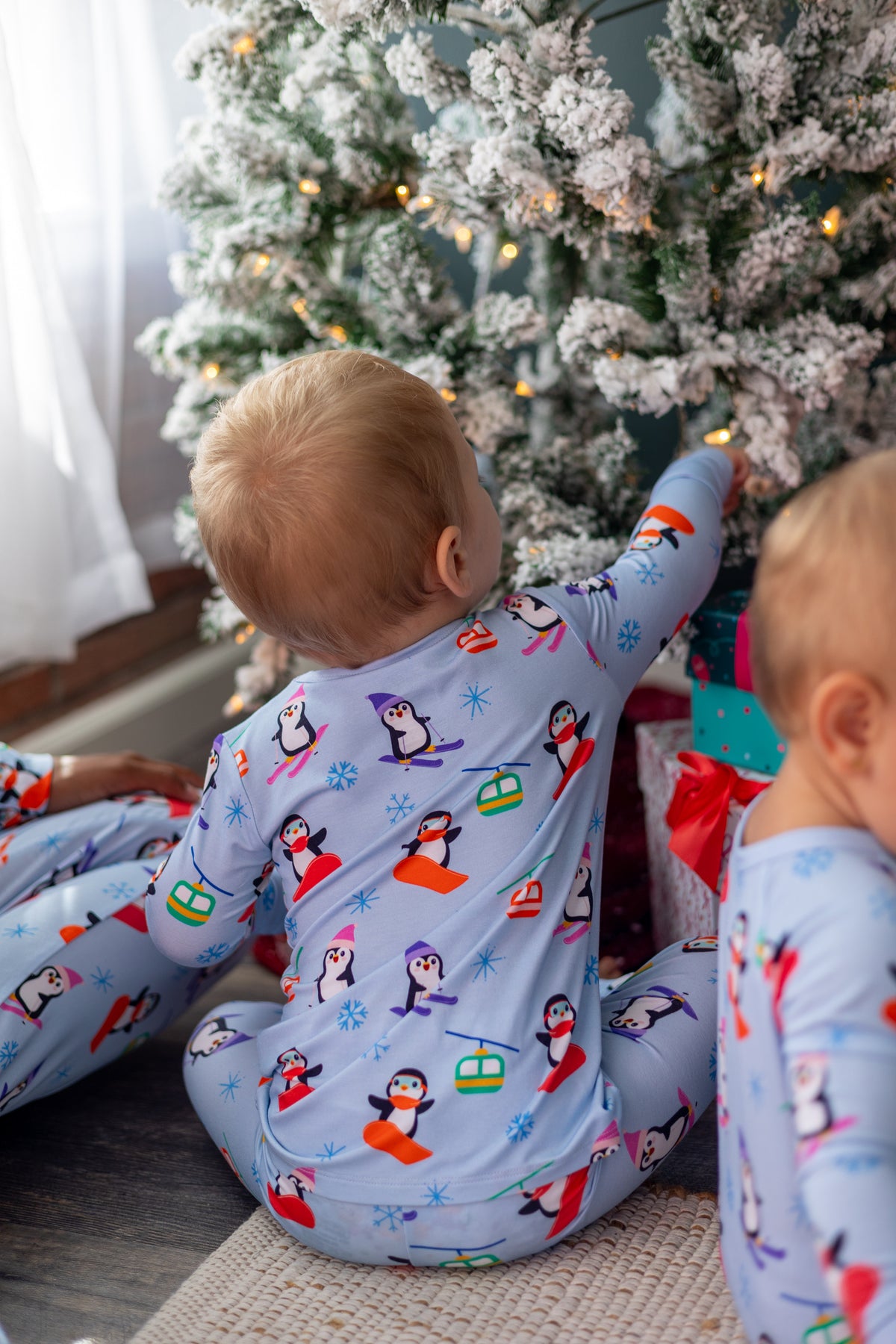 Kids' winter pajamas featuring colorful penguin patterns on soft blue fabric, perfect for cozy holiday moments.