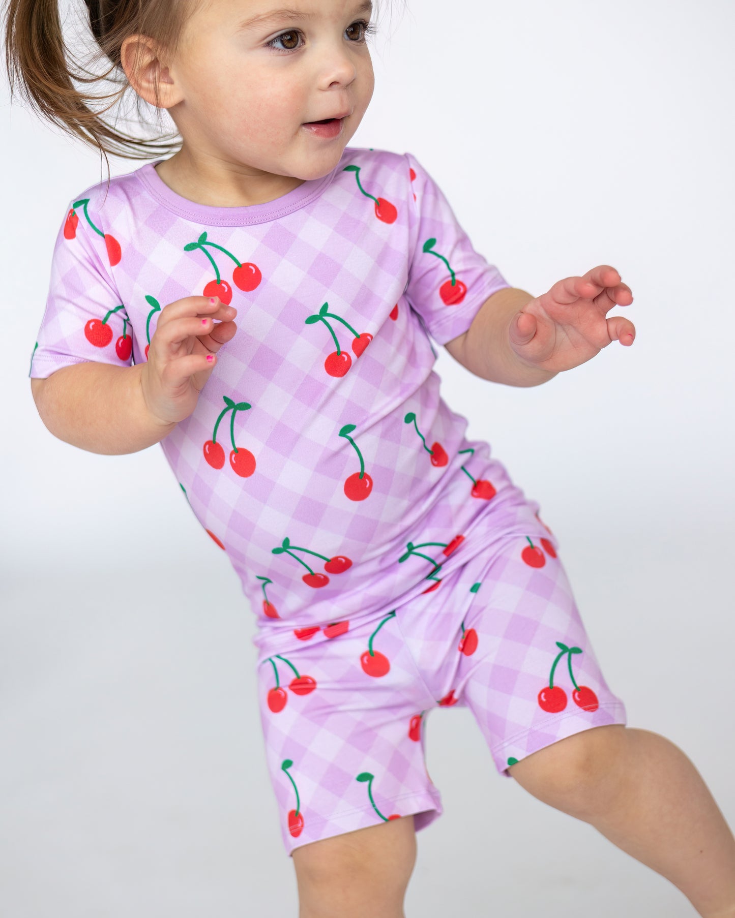 Toddler girls' cherry print outfit in lavender, short sleeves and shorts, made from soft, stretchy fabric.