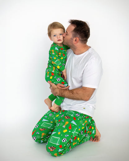 Father and child in matching green sport-themed pajamas, casual family moment.