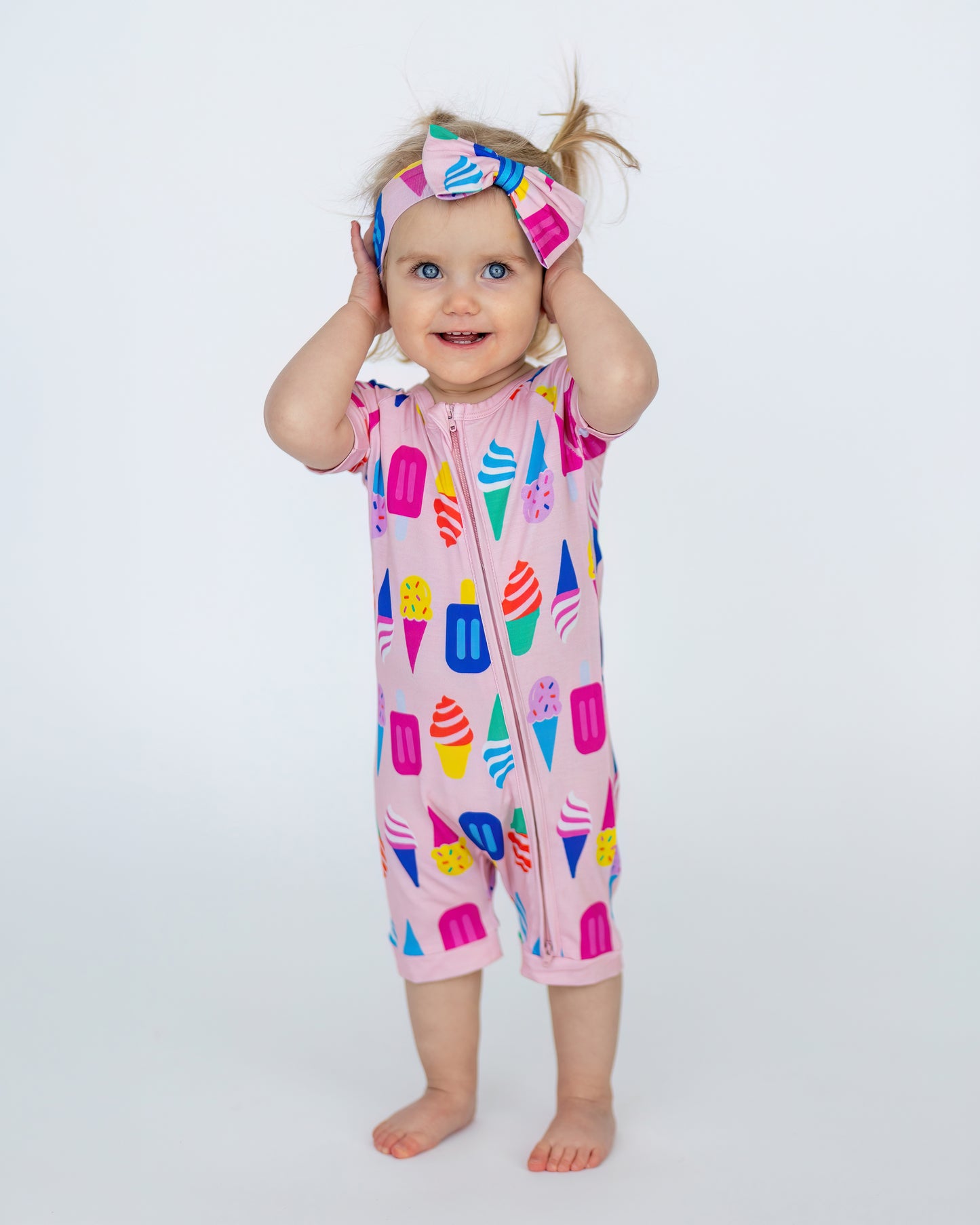 Cute toddler in a colorful ice cream print pink romper with matching headband, perfect for summer fun.