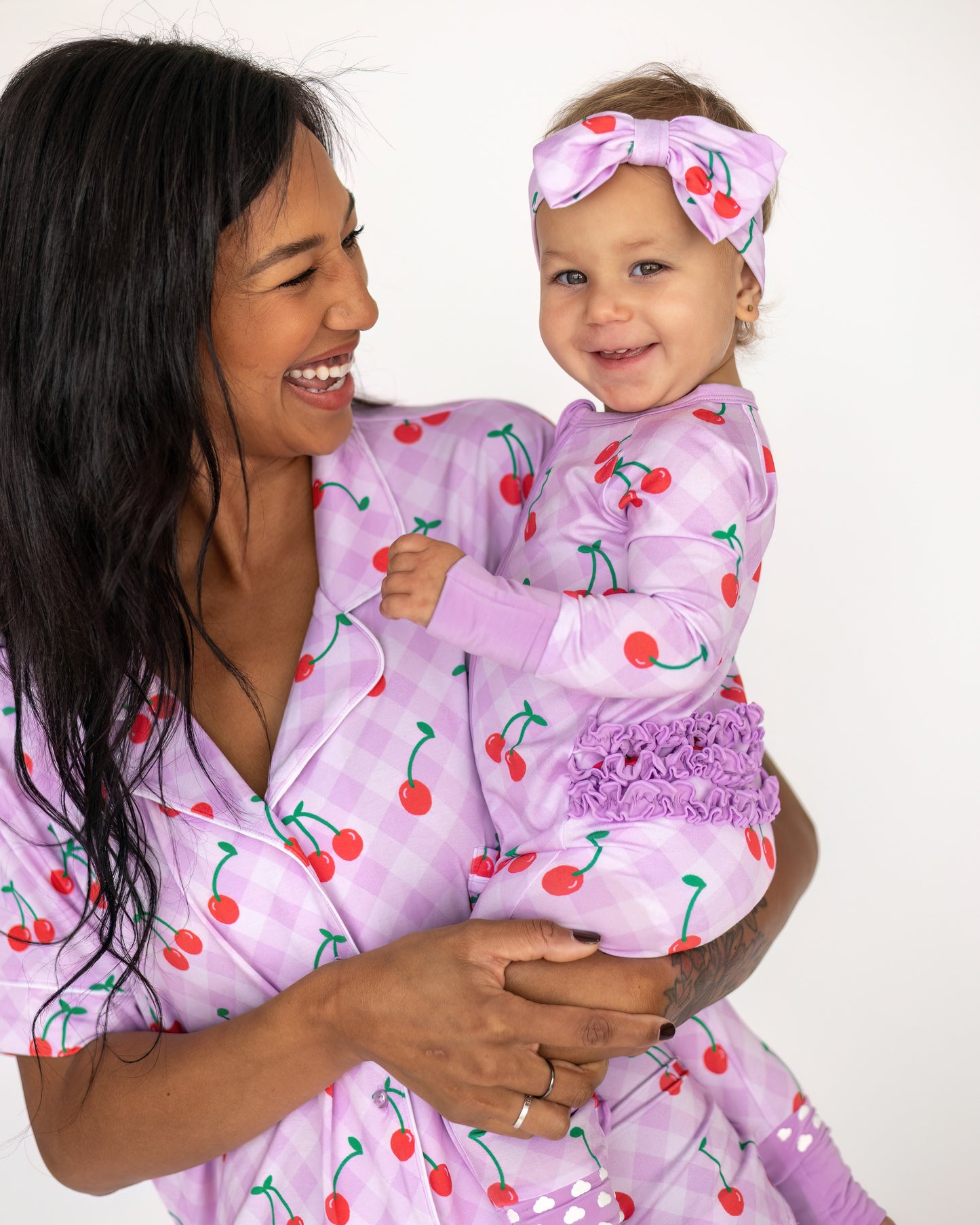 Matching cherry-print pajamas for mom and baby in lavender cotton with ruffled details.