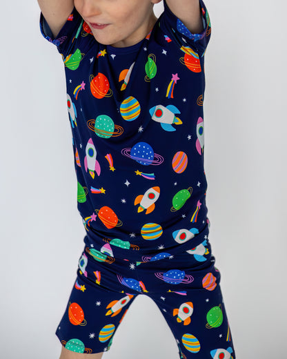 Boys' space-themed short set, navy blue with colorful rockets and planets, made from comfortable material.