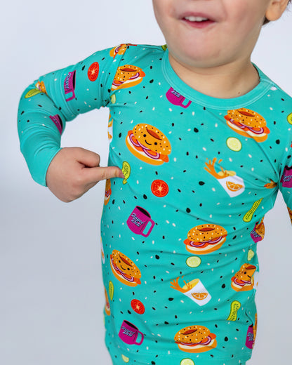 Kids' long-sleeve pajamas in turquoise with fun food print, featuring burgers, drinks, and snacks.