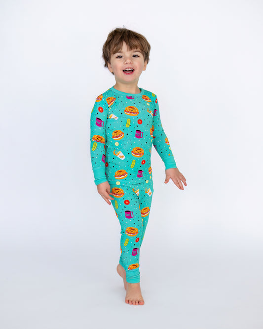 Kids' turquoise pajama set with fun food prints, made from soft stretchable fabric for comfort.