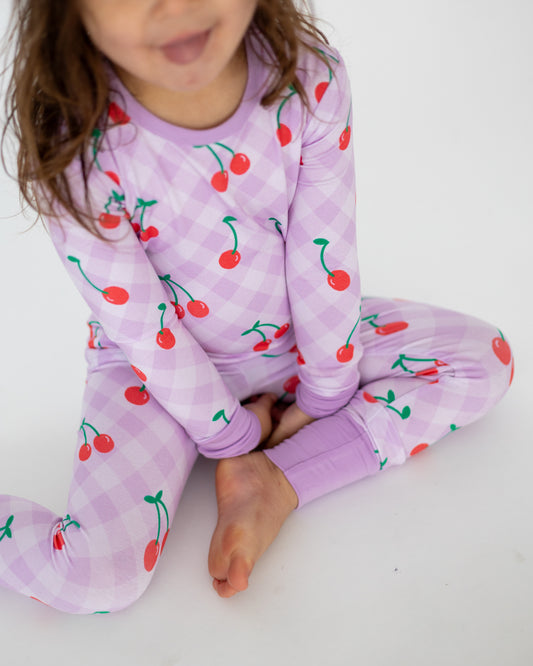 Kids' long sleeve pajamas in lavender with cherry print, made from soft cotton for comfort.