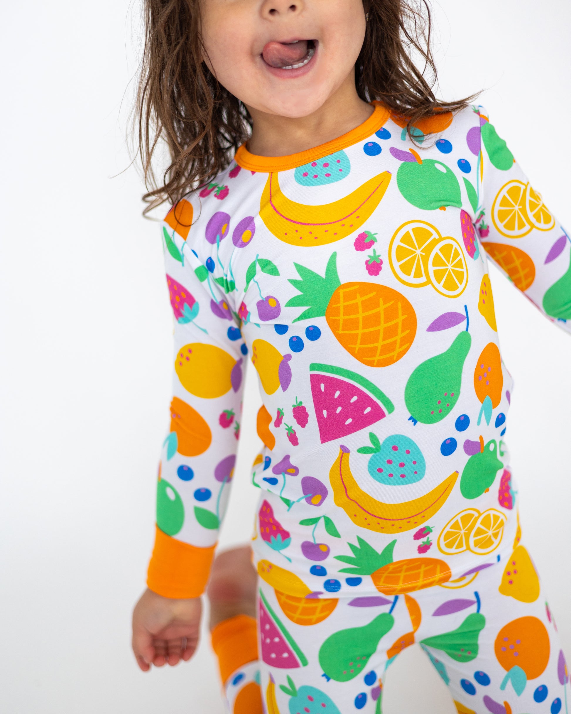 Colorful kids' pajamas set with fruit patterns, orange accents, made from soft, breathable fabric.