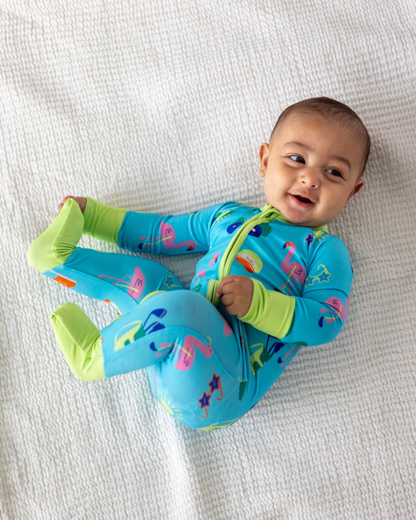 Infant unisex blue romper with colorful flamingo print, made from soft, breathable fabric.