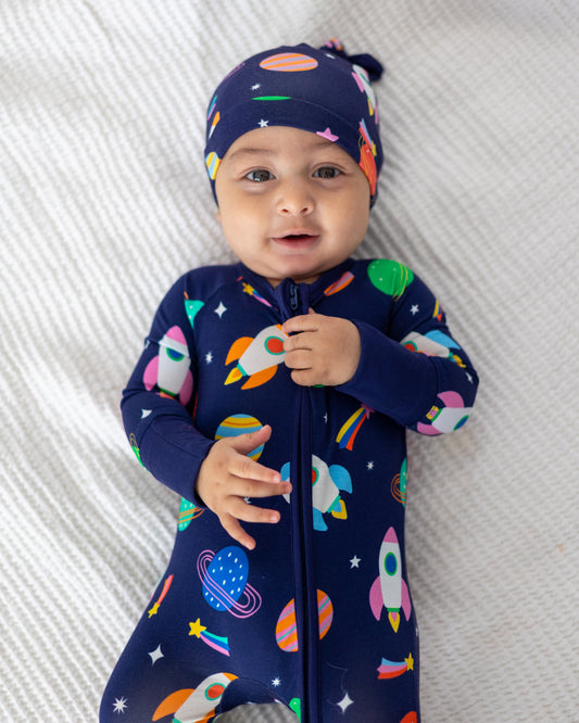 Navy blue baby sleeper with colorful rocket and planet prints, includes matching hat for stylish comfort.