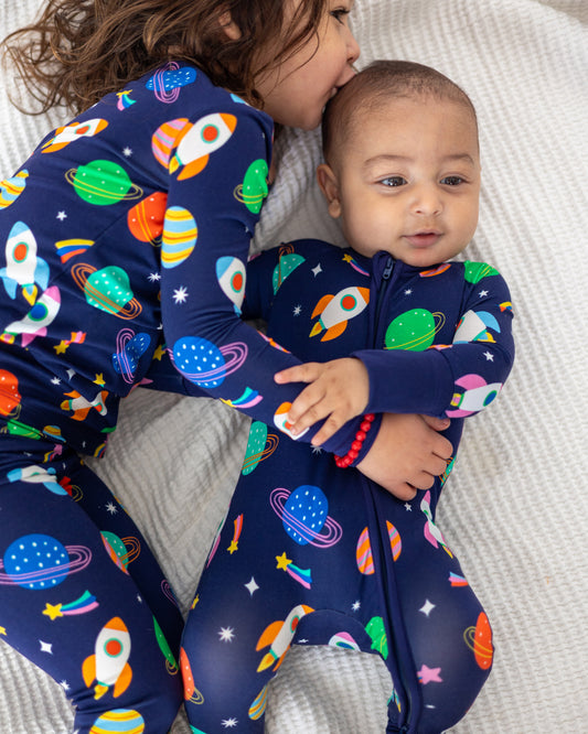 Navy space-themed pajamas for kids featuring rockets and planets, soft fabric, playful design.