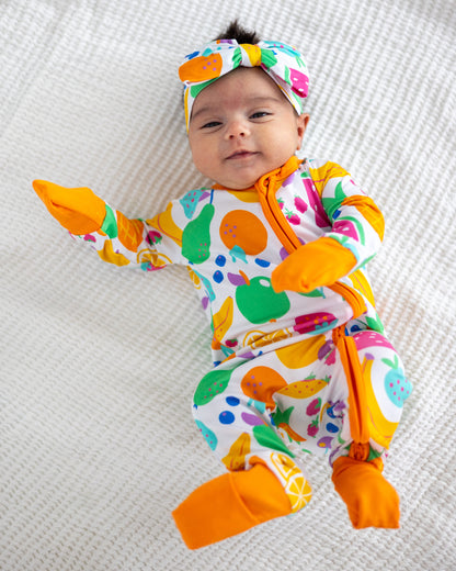Colorful baby onesie with fruit patterns, orange accents, soft material, and matching headband.