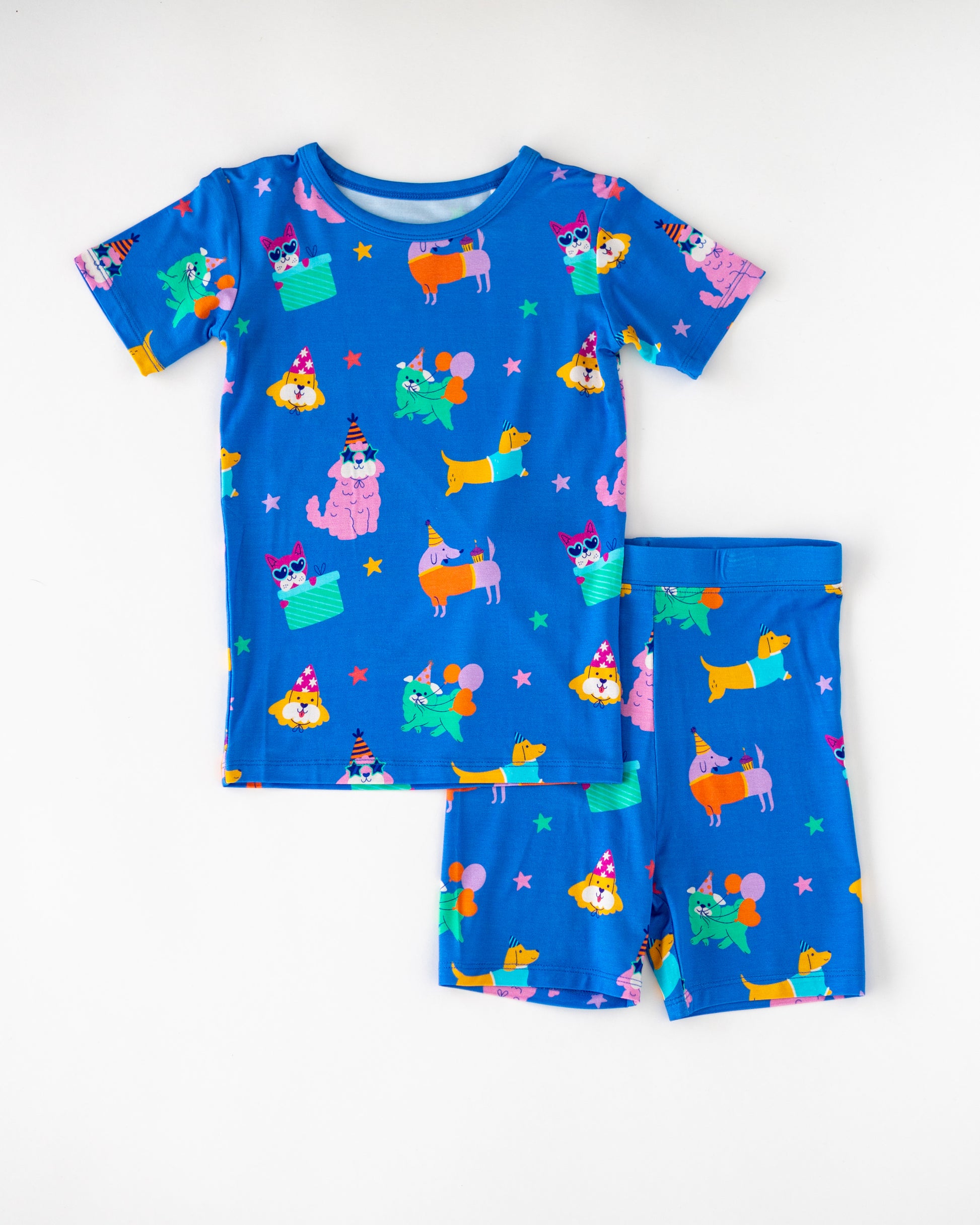 Colorful kids' short pajamas set, featuring playful dog and cat designs on blue fabric.