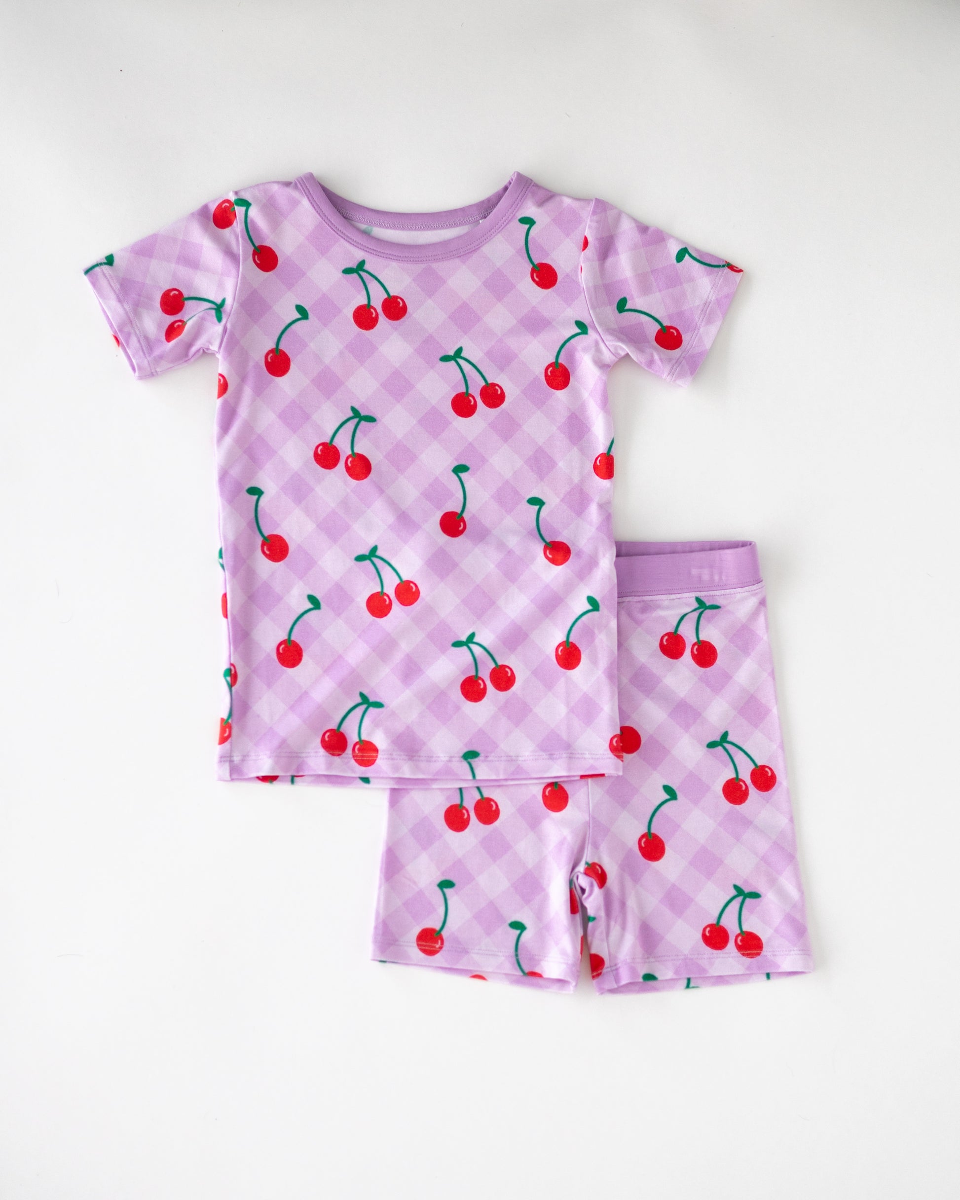 Children's purple cherry print pajamas set, short sleeve top and shorts, made from soft breathable fabric.