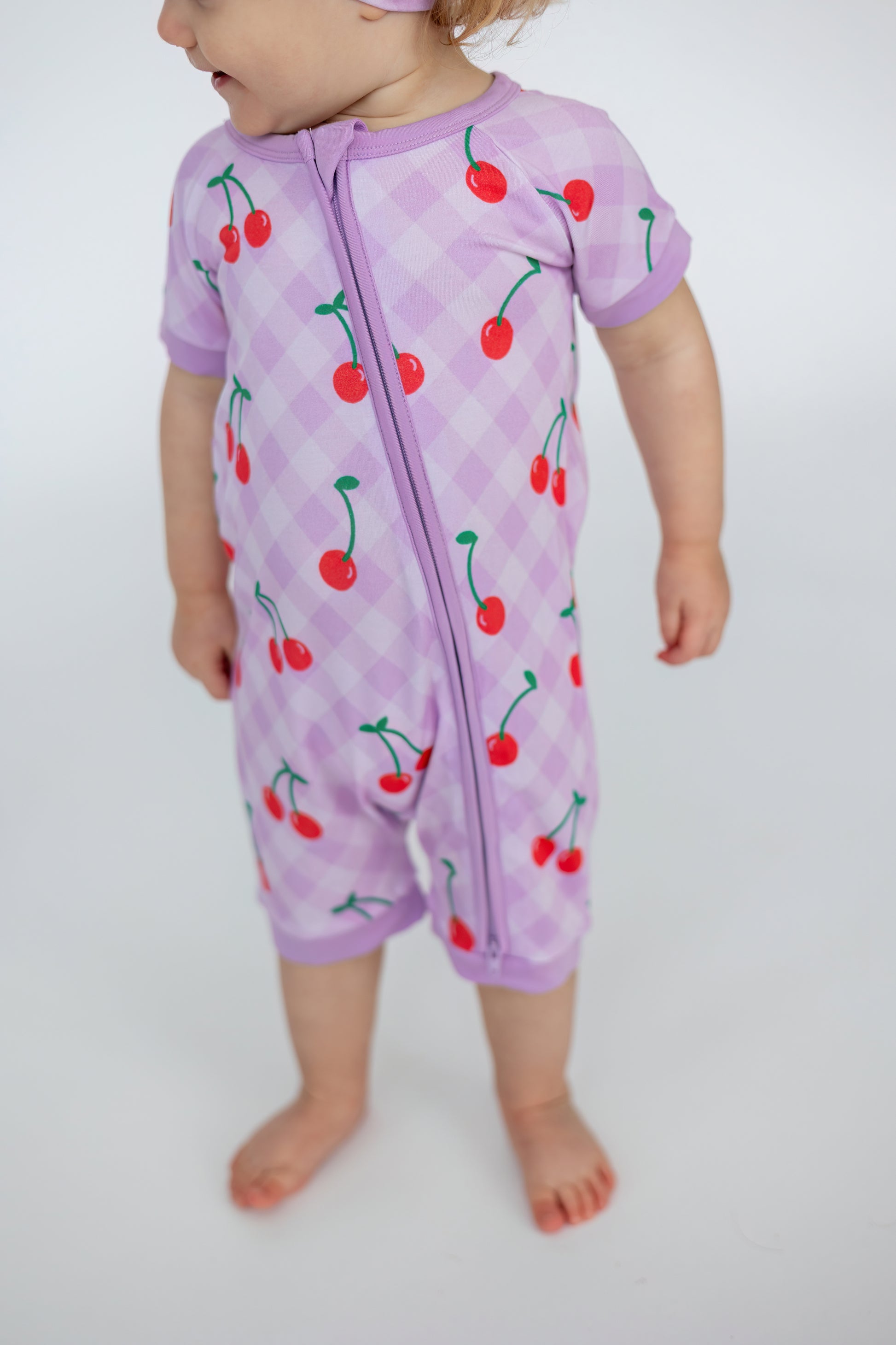 Toddler cherry print romper in lavender, featuring short sleeves and a front zipper for easy dressing.
