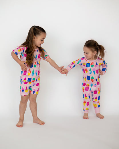 Girls' playful matching pajamas in pink with ice cream and popsicle print, made from soft, breathable fabric.