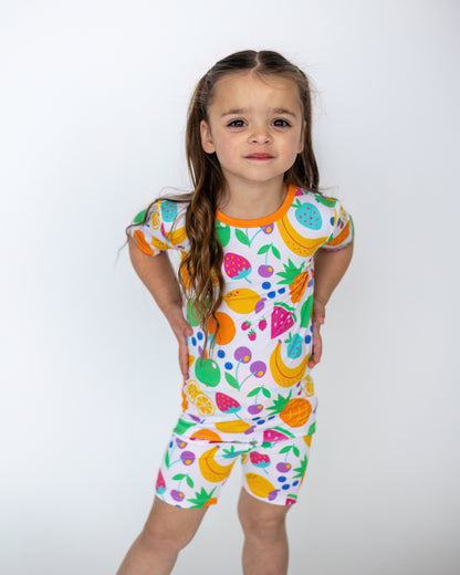 Colorful fruit-patterned toddler short set in soft fabric, featuring oranges, strawberries, and bananas.